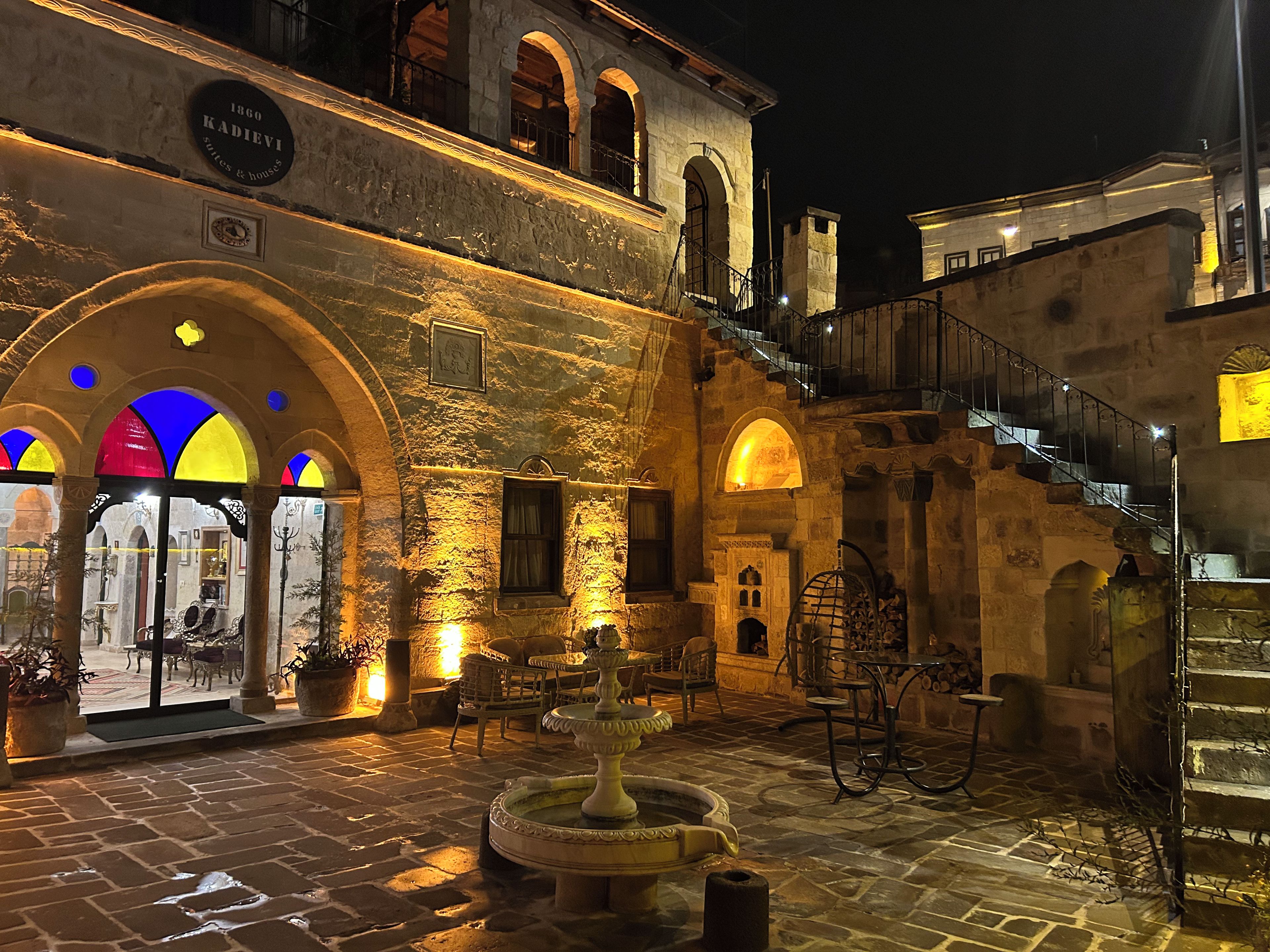 A historic building with stone architecture, a courtyard with a fountain, and outdoor seating.