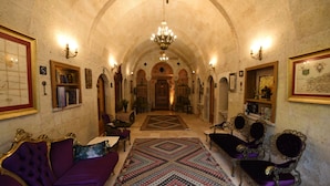 A grand hallway with a patterned carpet, ornate furniture, and a chandelier.
