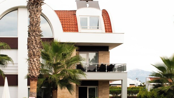 Ein modernes Haus mit zwei Etagen, einem Pool, Palmen und Blick auf die Berge.