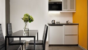 A compact kitchen with a dining area, featuring a black table and chairs, a small island with a sink, and a potted plant. - FH55 Med Guesthouse (Florence)