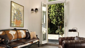 A room with two leather sofas, a framed floral artwork, and a door leading to an outdoor area with trees. - FH55 Med Guesthouse (Florence)