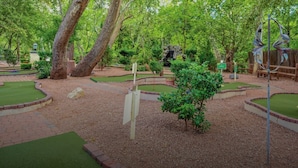A miniature golf course with sand traps, a small pond, and a wooden bridge.