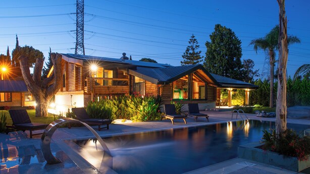 A modern house with a swimming pool, lounge chairs, and a well-lit patio area.