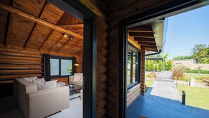 A log cabin interior with a sofa, television, and a view of the outdoors.