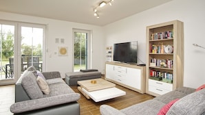 Una sala de estar moderna con un sofá gris, una mesa de centro, un televisor y una estantería.