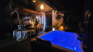 Une pièce faiblement éclairée, avec une grande piscine bleue, un lit à baldaquin et plusieurs plantes en pot.