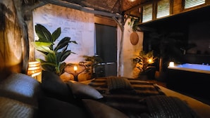 Un salon confortable avec un canapé, des coussins, une petite table et des plantes en pot.
