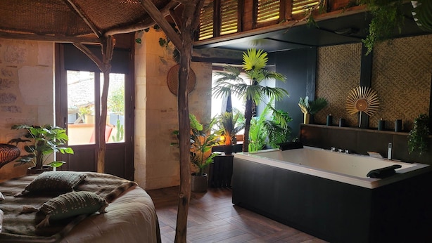 Une salle de bain moderne avec une baignoire sur pieds, entourée d’une végétation tropicale luxuriante.