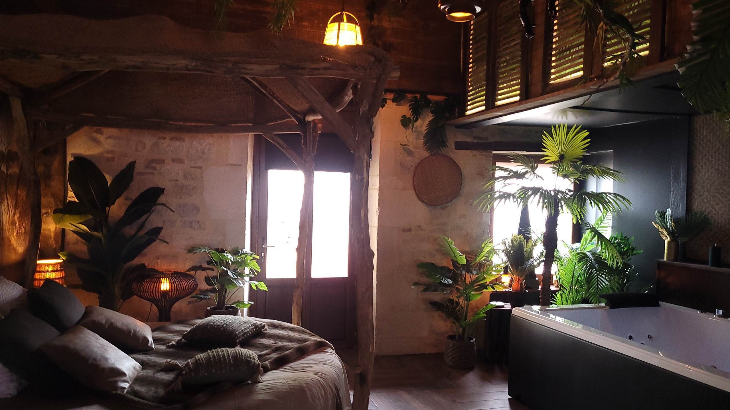A cozy room with a bed, a bathtub, and various plants.