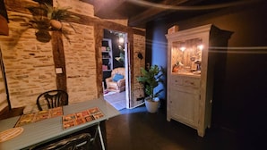 Une pièce chaleureuse avec un mur en pierre, un meuble en bois décoré sur le thème du café, une table avec un menu et un fauteuil confortable.