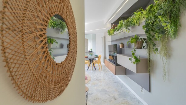 A modern interior with a woven wall art piece and shelves with green plants. - Como Panorama in Como (Como)