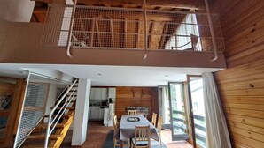 Un intérieur moderne comprenant un coin repas, une cuisine et un escalier en bois menant à une mezzanine.