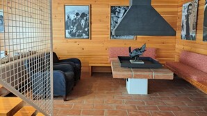 L’intérieur d’un chalet en bois comprend une cheminée, un coin salon et des tableaux accrochés au mur.