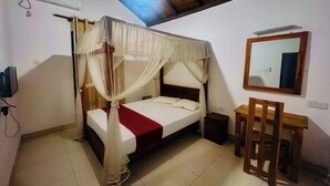 A room with a bed under a canopy, a wooden desk, a mirror, and an air conditioning unit.