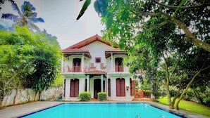 A two-story house with a swimming pool in front.