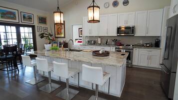 A modern kitchen with white cabinets, stainless steel appliances, and a central island with bar stools.