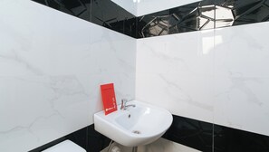 A bathroom with a white sink, black and white tiled walls, and a red towel hanging on the wall. - Reddoorz Near Lrt 2 Antipolo Station (Antipolo)