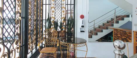 A room with a black and gold gate, a round table, and a chair.