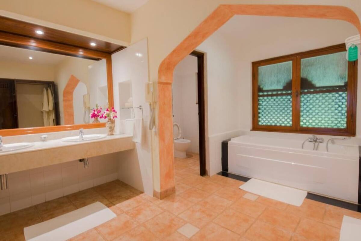 Une salle de bain avec un double vasque, une baignoire, un grand miroir et une fenêtre donnant sur un paysage attrayant.