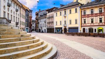 Ein Kopfsteinpflasterplatz mit historischen Gebäuden, einer Steintreppe und Außenbestuhlung.