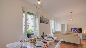 A dining area with a table set for four, a sofa, and a TV in the background. - Bellinzona in Centro (Bellinzona)