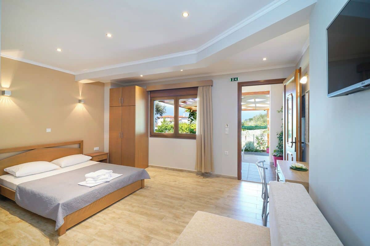 A hotel room with a bed, a desk, a TV, and a view of the outdoors.