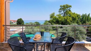 A covered outdoor area with a table and chairs, overlooking a scenic view of the sea and greenery. - Kapsogeorgis Rooms (Thasos)