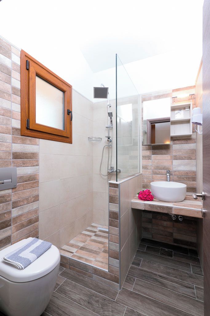 A modern bathroom with a glass shower enclosure, a white toilet, and a vanity with a sink.