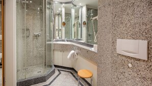 A modern bathroom with a glass-enclosed shower, a sink with a mirror above, and a toilet with a white towel.