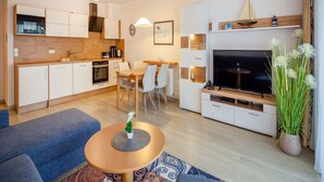A modern apartment with a kitchen, dining area, living room, and a TV.