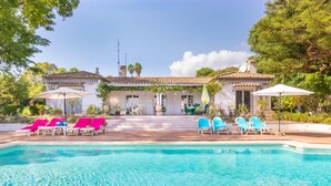A pool area with lounge chairs and umbrellas, surrounded by a building with a tiled roof and steps leading up to it. - Cortijo Villa Padierna El Lago (Benahavis)
