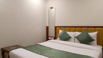 Una habitación de hotel con una cama, una mesita de noche, un espejo y un cabecero de madera.