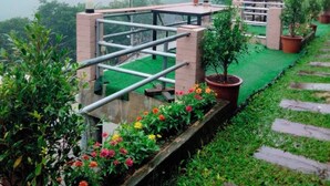 A rooftop terrace with a metal railing, potted plants, and a green artificial turf. - Mon Nao  (Mae Rim)