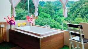 A bathroom with a large bathtub, a sink, and a chair. There are curtains and a welcome mat. - Mon Nao  (Mae Rim)