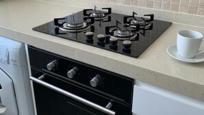 A kitchen with a gas stove, oven, and a cup on the counter. - London Retreat at Hindsley's Place (London)