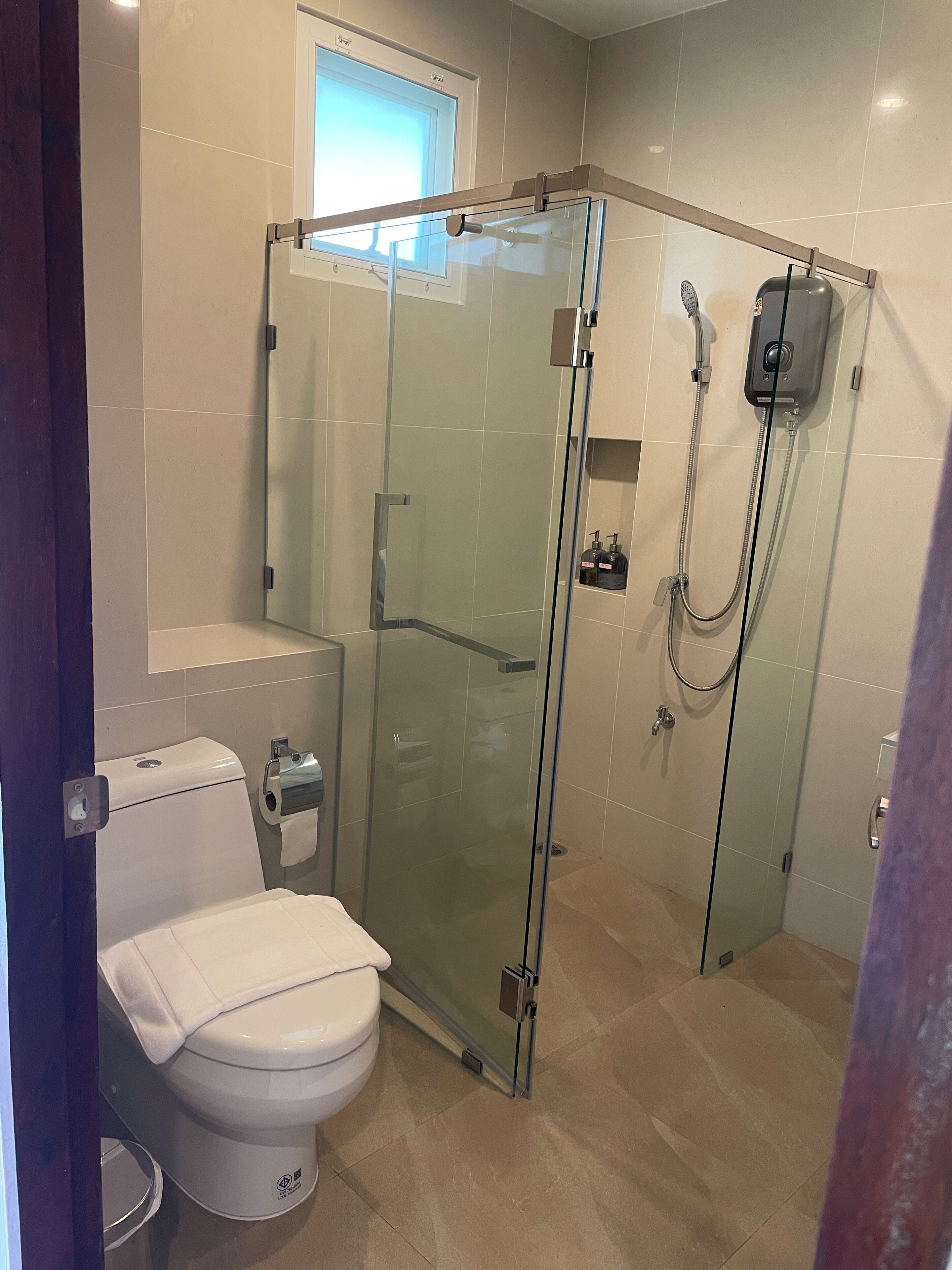 A modern bathroom with a glass-enclosed shower, a toilet, and a sink.