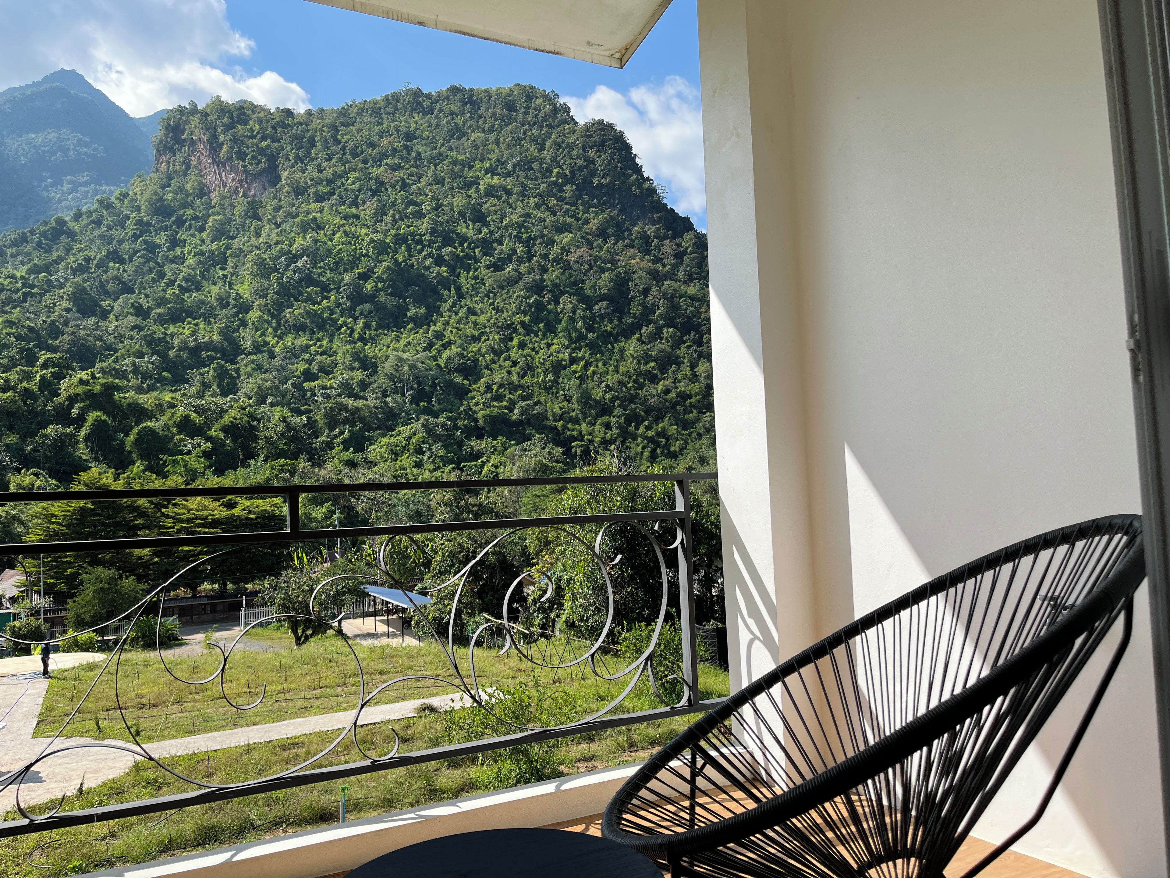 A balcony with a view of a mountainous landscape, a chair, and a railing.