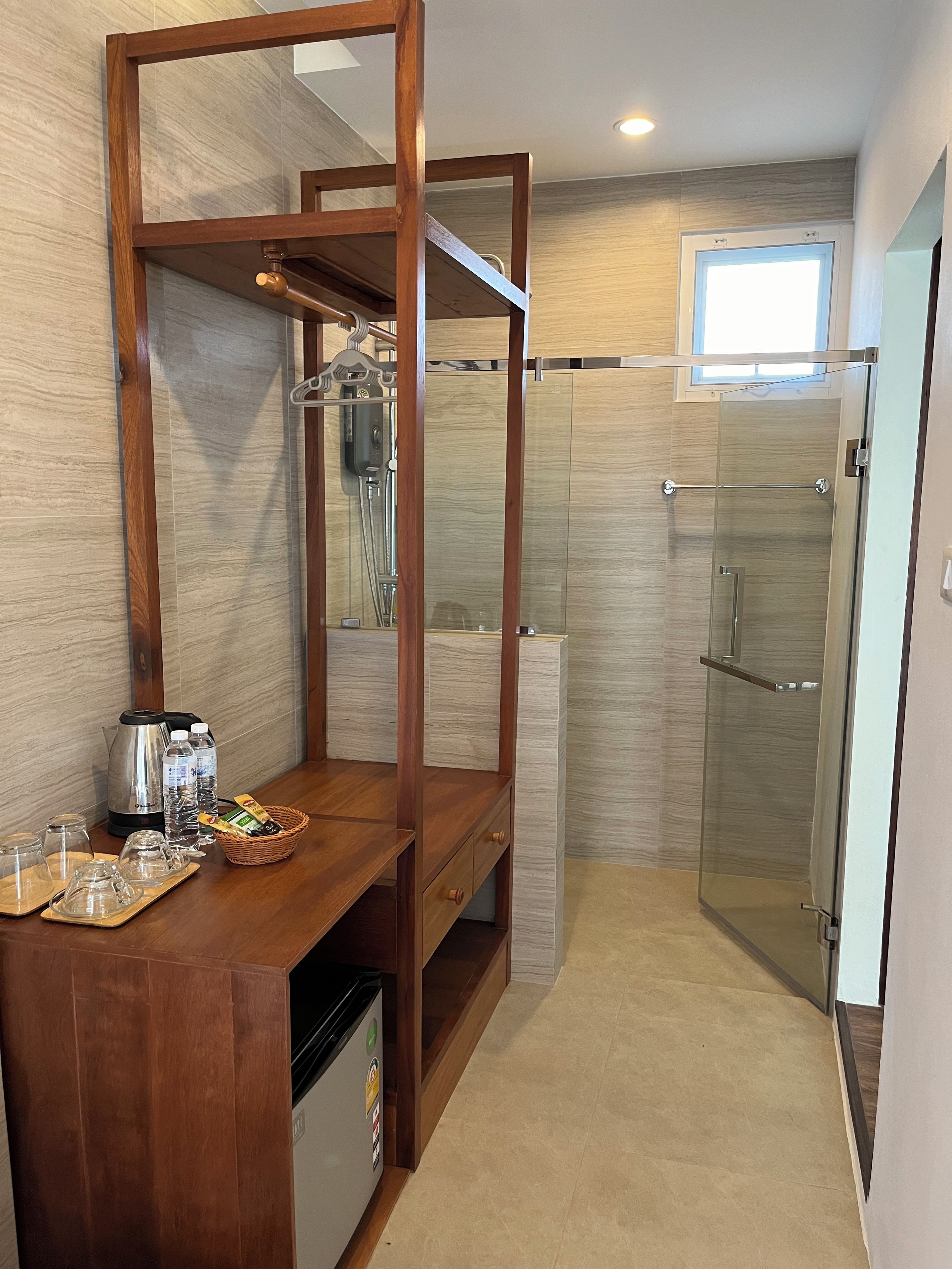 Un baño moderno con tocador de madera, cabina de ducha y un refrigerador pequeño.