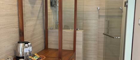 Un baño moderno con tocador de madera, cabina de ducha y un refrigerador pequeño.