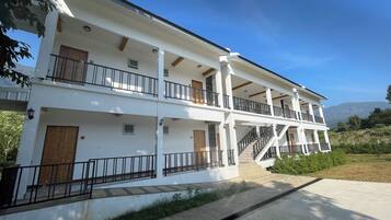 A multi-story building with balconies, a staircase, and a view of the surrounding landscape.