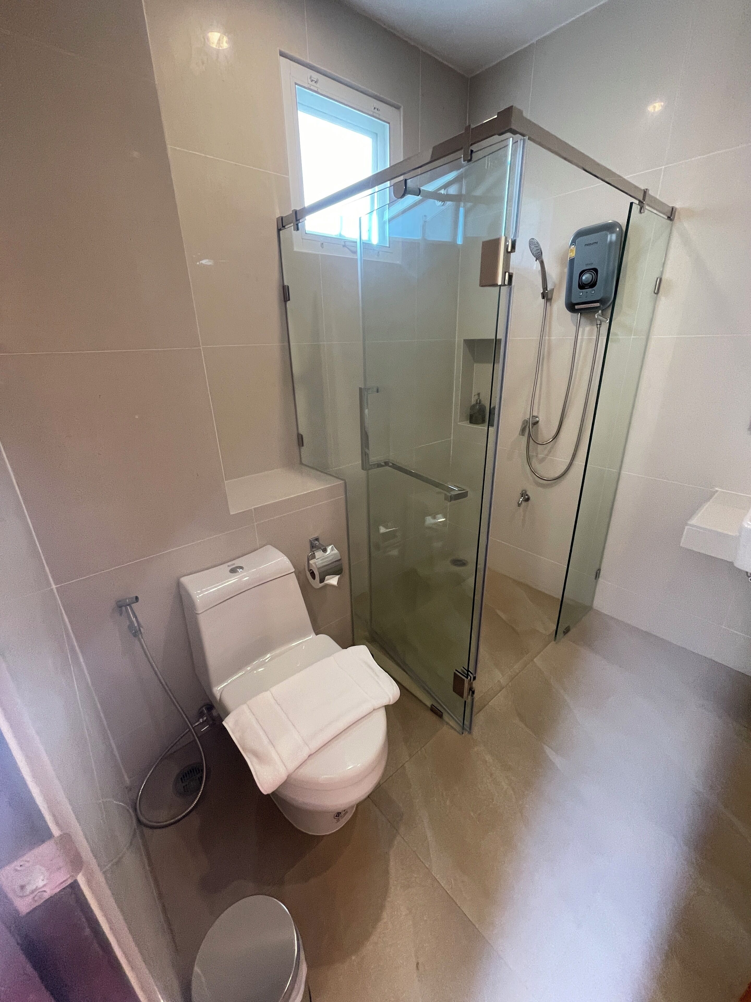 A modern bathroom with a glass-enclosed shower, a toilet, and a sink.