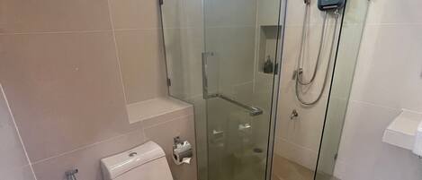 A modern bathroom with a glass-enclosed shower, a toilet, and a sink.