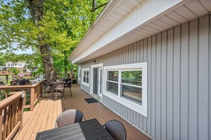 A deck with outdoor furniture, a large tree, and a house with a white exterior and windows. - The Lake Effect House (Dublin)