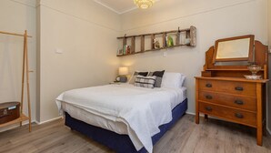 A bedroom with a bed, a dresser, a shelf with books, and a wooden ladder. - Lake Court in the heart of Forster (Forster)