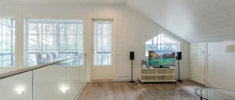 Ein geräumiges Zimmer mit Holzboden, einer Glasreling und einem großen Fenster.