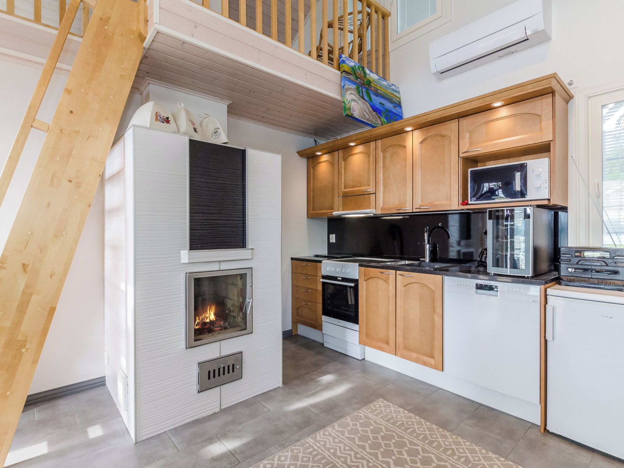 A modern kitchen with a built-in fireplace, wooden cabinets, and a stainless steel range hood.