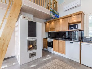 A modern kitchen with a built-in fireplace, wooden cabinets, and a stainless steel range hood. - Levähdys by Interhome (Joensuu)