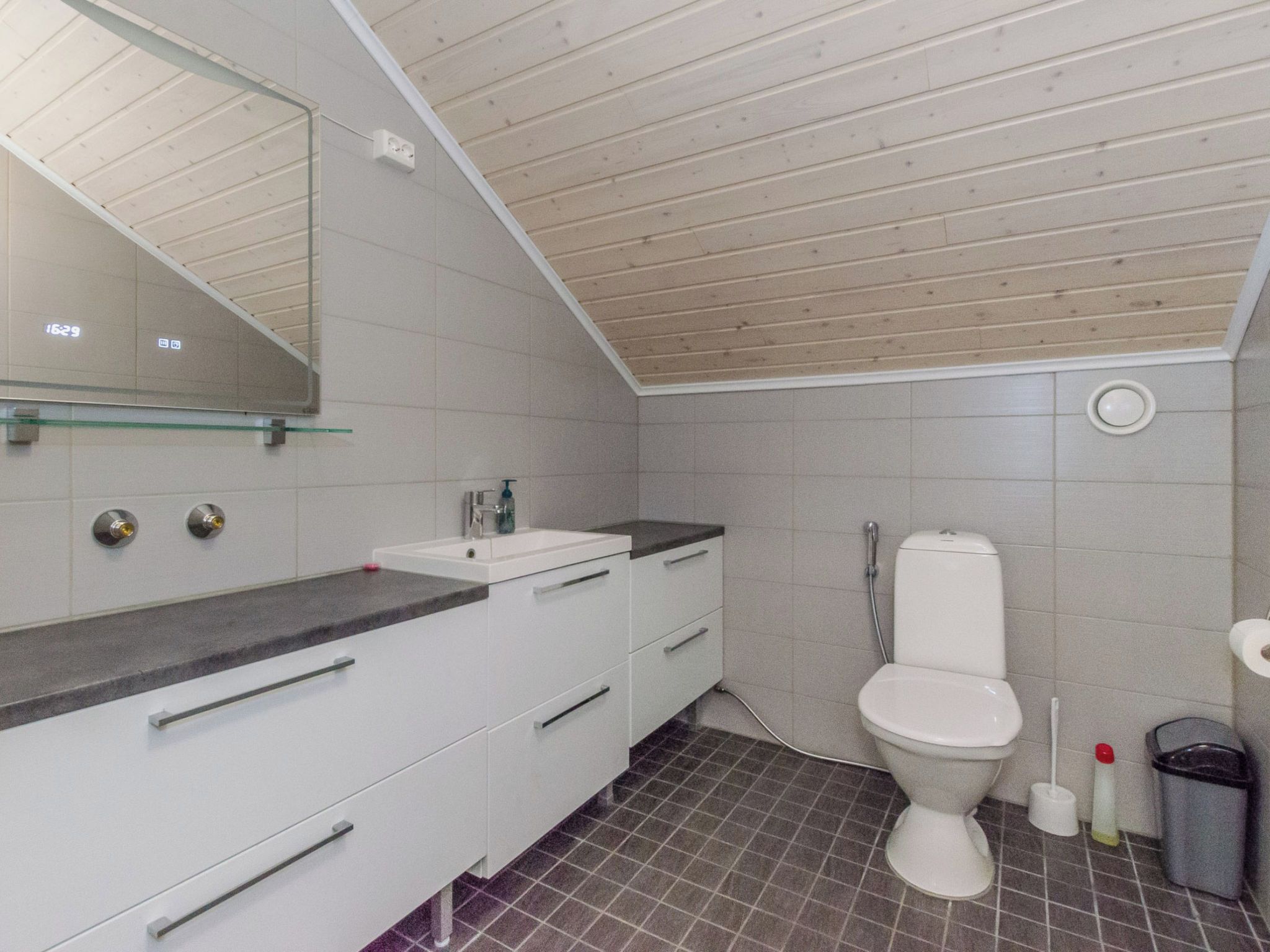 Ein modernes Badezimmer mit Holzboden, einem weißen Waschbecken und einer Toilette.