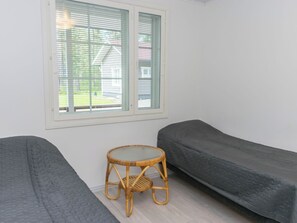 A room with two single beds, a small round table, and a window with blinds. - Levähdys by Interhome (Joensuu)