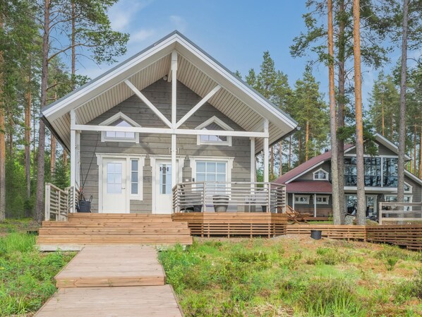 A cabin with a wooden deck, a covered porch, and a large window.